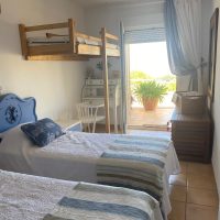 white and blue bedroom with two beds and an additional bed for a kid